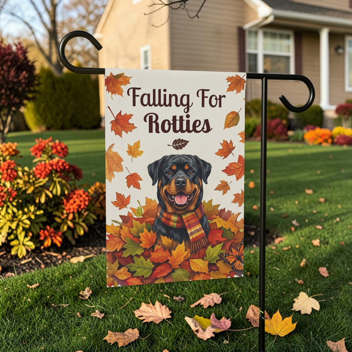 Falling For Rotties Rottweiler garden flag on its stand on a lawn framed by autumn foliage and colorful garden beds