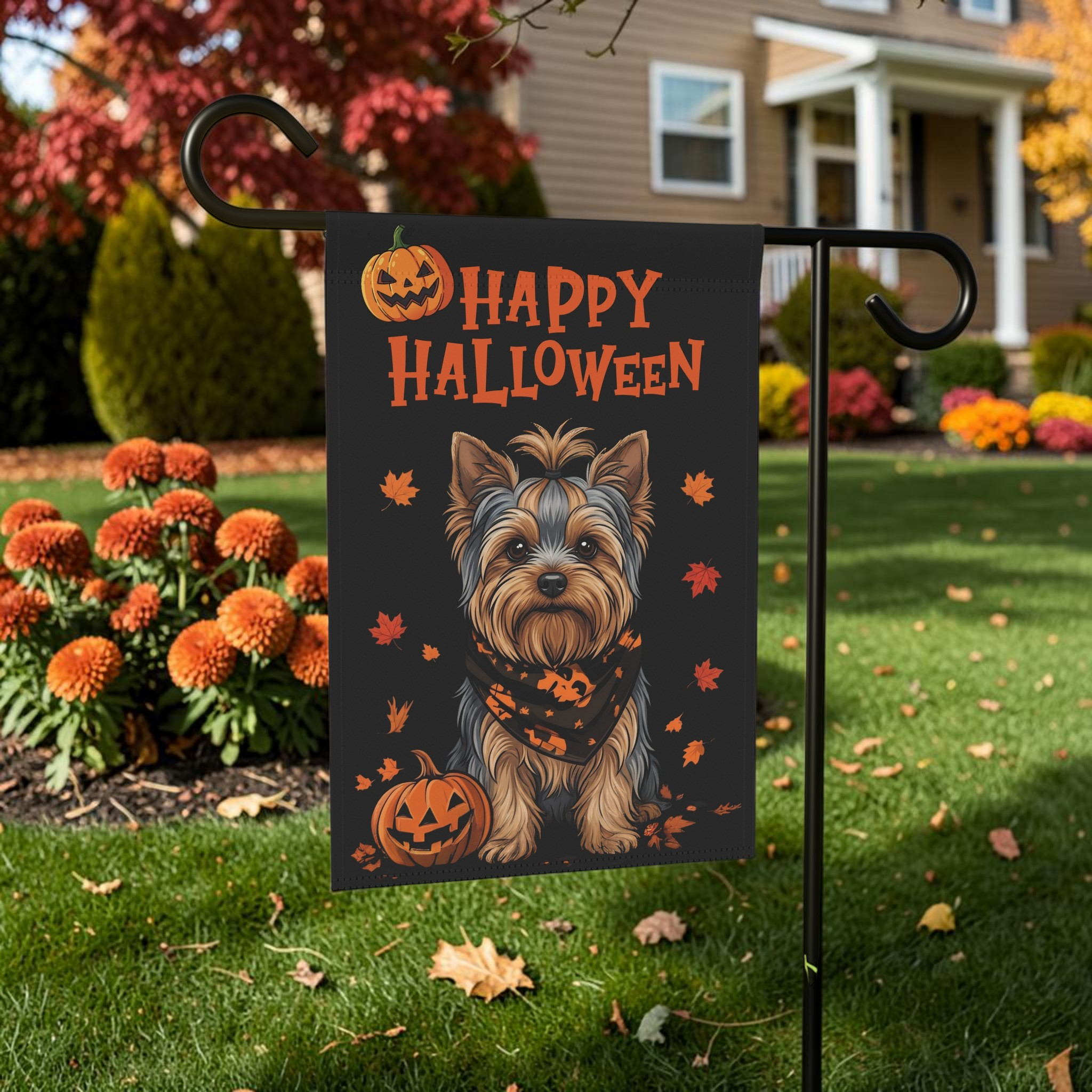 Little Pumpkin Yorkshire Terrier Halloween garden flag on a stand near autumn flowers and trees in a front yard