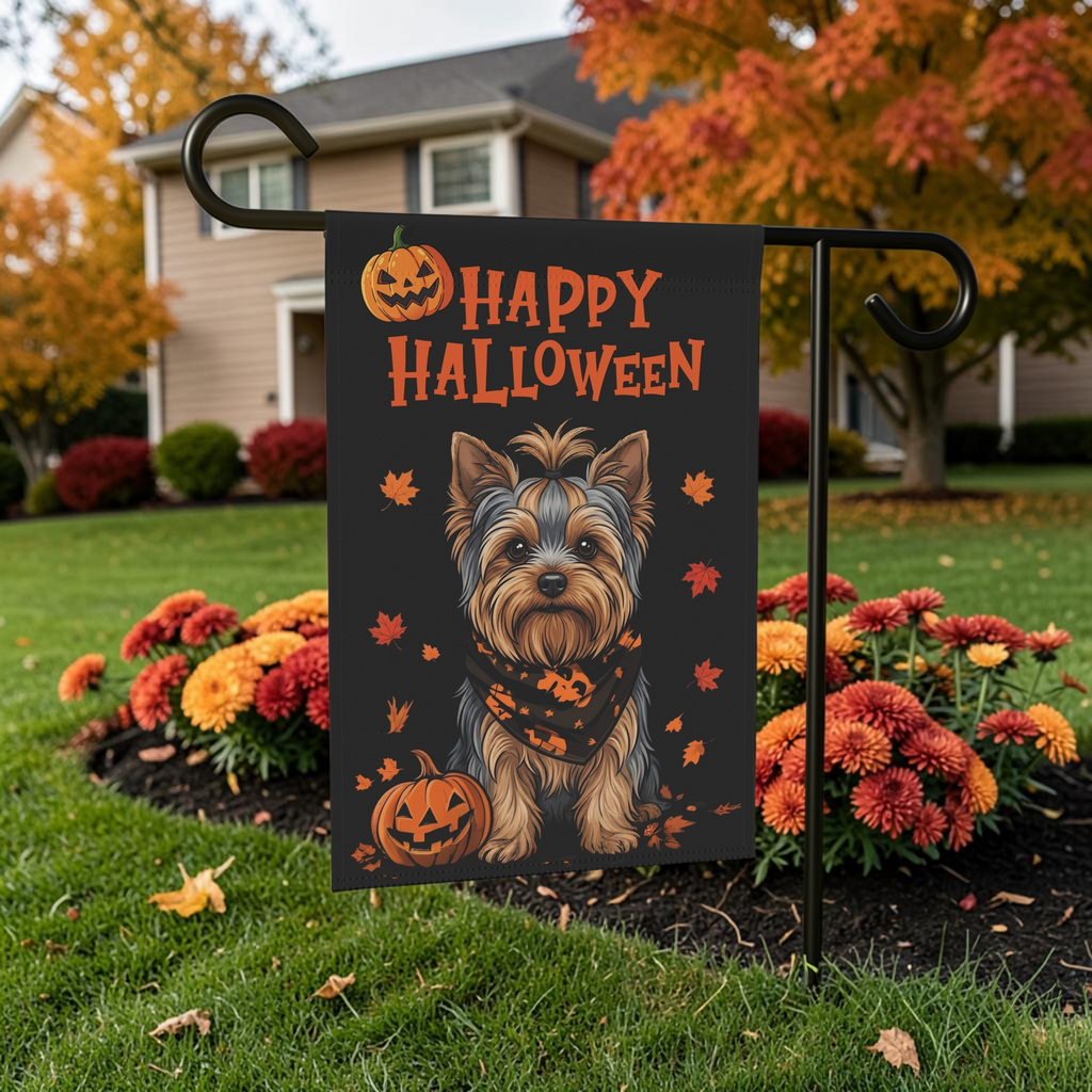 Little Pumpkin Yorkshire Terrier Halloween garden flag displayed on its stand among orange mums with an autumn tree in the background