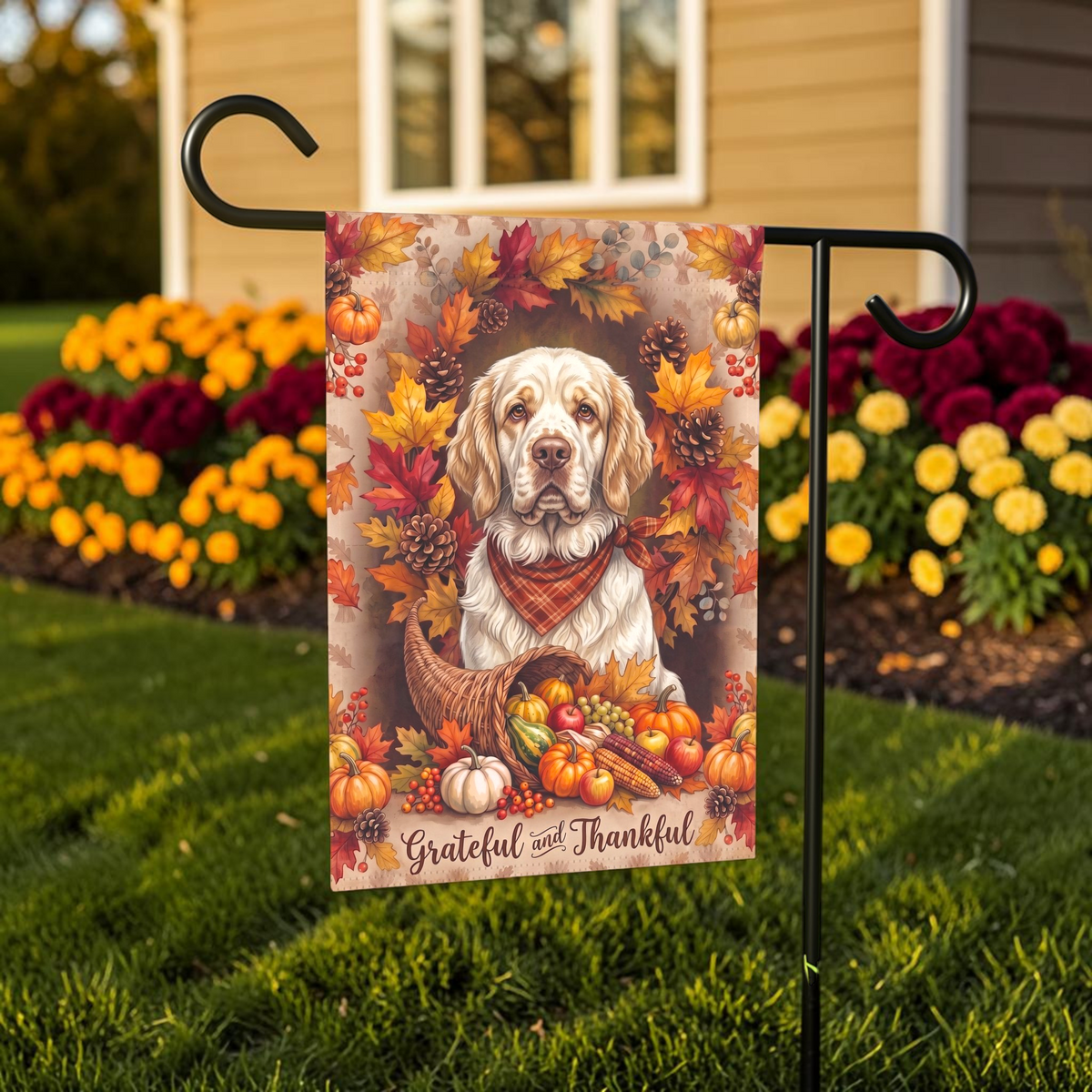 Grateful and Thankful Clumber Spaniel Thanksgiving garden flag shown on a stand near a walkway with potted mums