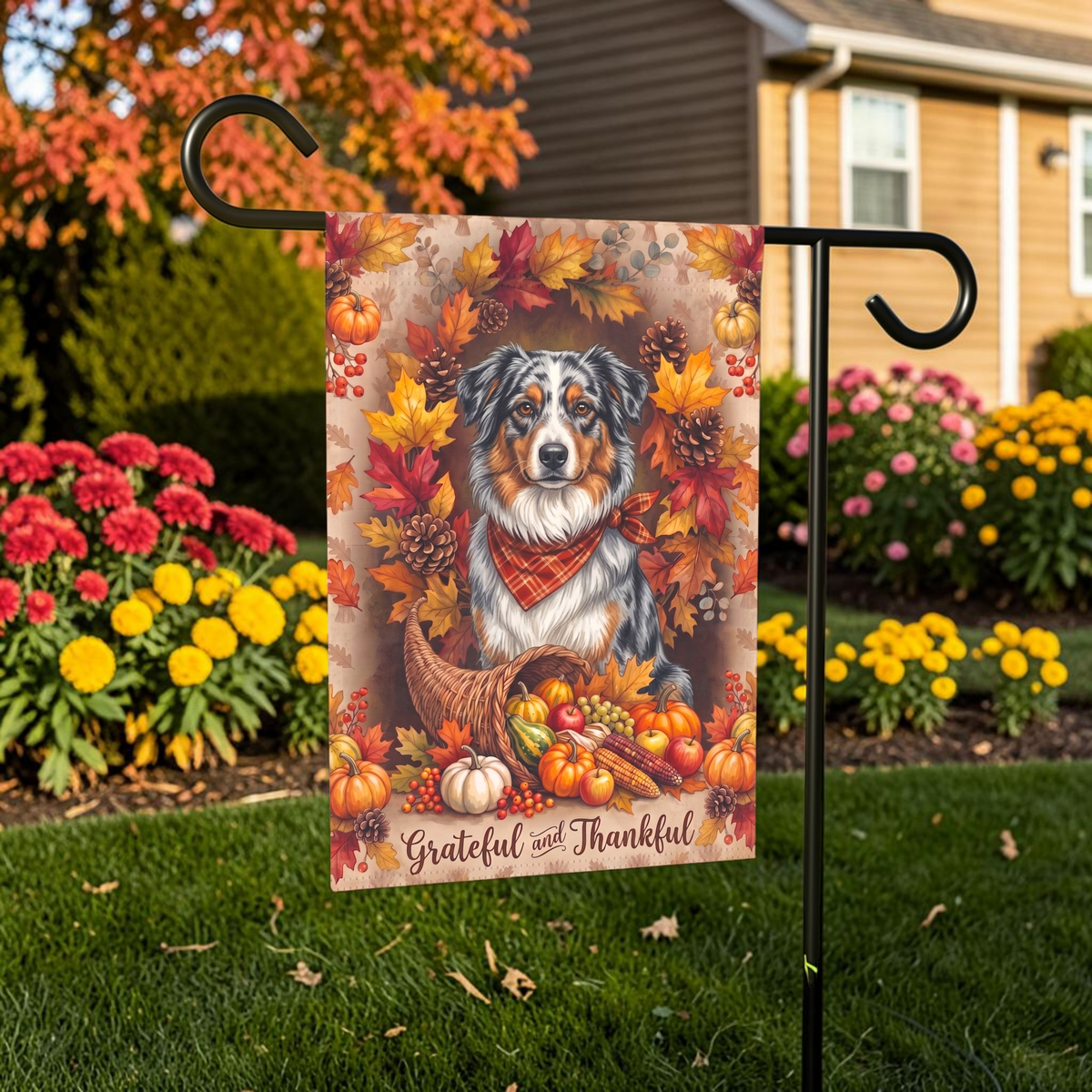 Grateful and Thankful Australian Shepherd Garden Flag garden flag displayed on a stand in a garden bed with autumn flowers and a house in the background