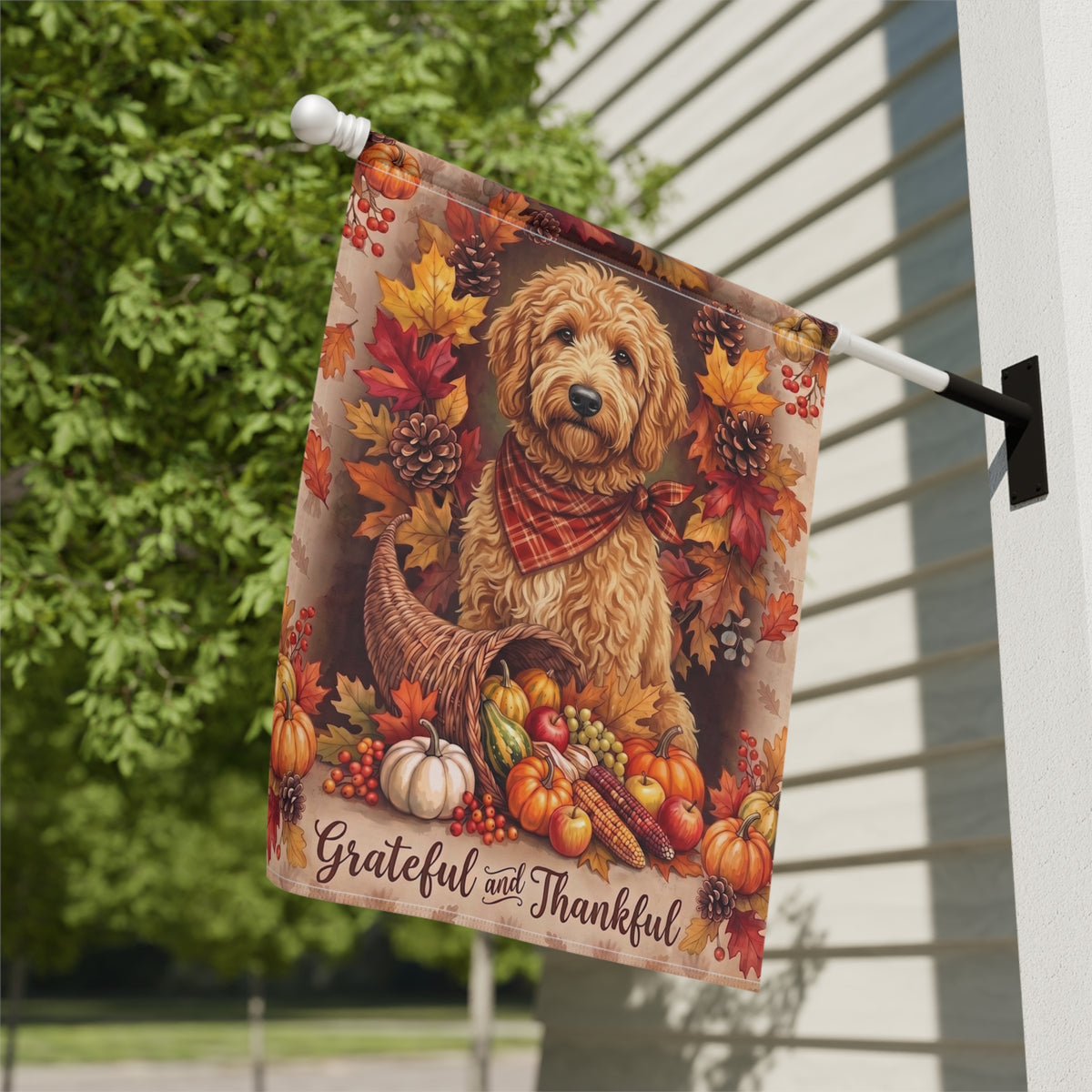 Grateful and Thankful Doodle Golden Noodle house flag mounted on a wall bracket at a diagonal angle against a house exterior